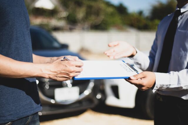 Customers and car insurance agents finalize agreements and sign documents to process compensation claims following a car accident, highlighting an essential aspect of insurance procedures.